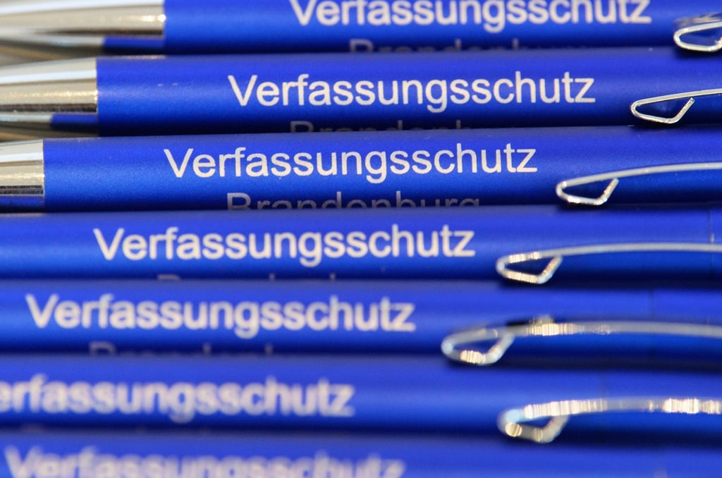Kugelschreiber mit der Aufschrift „Verfassungsschutz“ liegen auf einem Tisch.