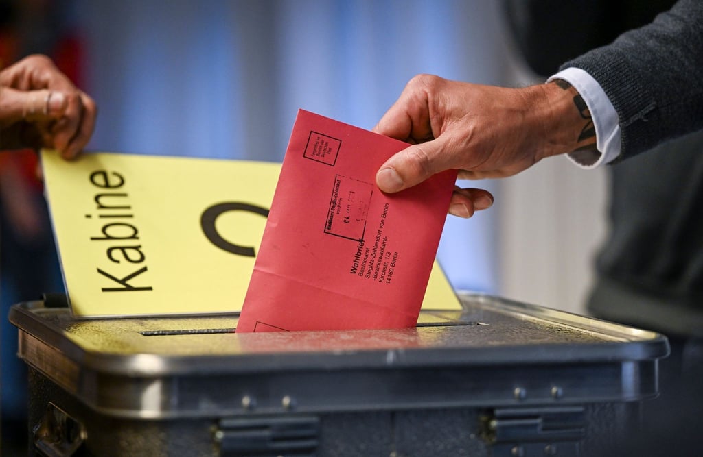 Ein Mann steckt seine Stimmzettel in einem Briefumschlag in die Wahlurne.