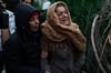 Frauen weinen, während sie zusehen, wie die Rettungskräfte in den Trümmern eines zerstörten Gebäudes in Adana nach Menschen suchen.