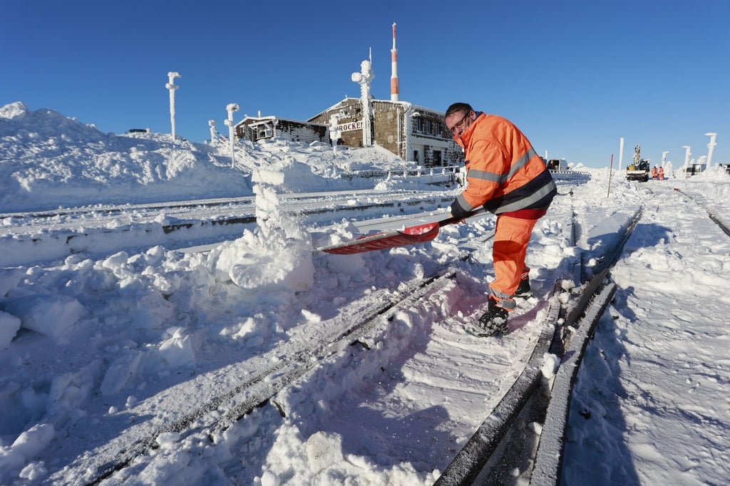 Ein Mitarbeiter der Harzer Schmalspurbahn räumt Schnee aus den Gleisen am Brockenbahnhof.