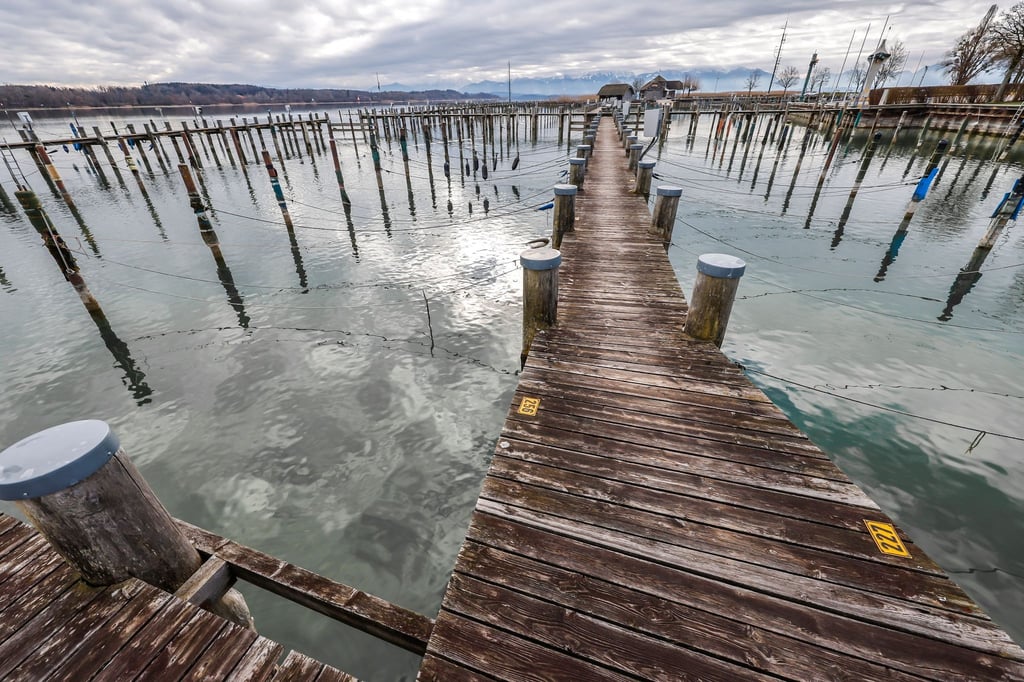 Leere Bootsstege spiegeln sich bei Temperaturen um den Gefrierpunkt im Wasser des Chiemsees.