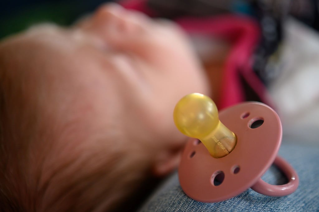 Ein zwei Wochen altes Neugeborenes liegt auf dem Schoß seiner Mutter.