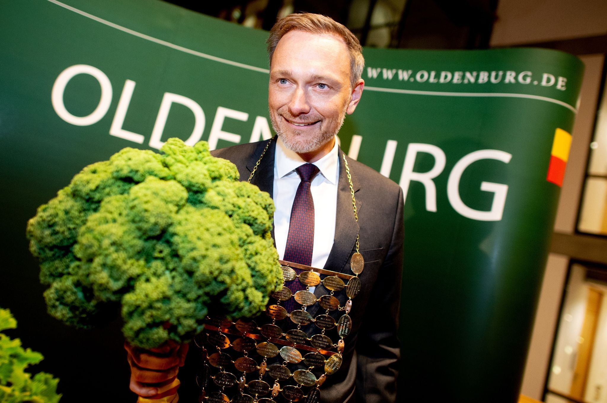 Der neue Oldenburger Grünkohlkönig Christian Lindner (FDP), Bundesfinanzminister, trägt eine Kohlkette und hält eine Grünkohlpflanze, auch bekannt als „Oldenburger Palme“, in den Händen.