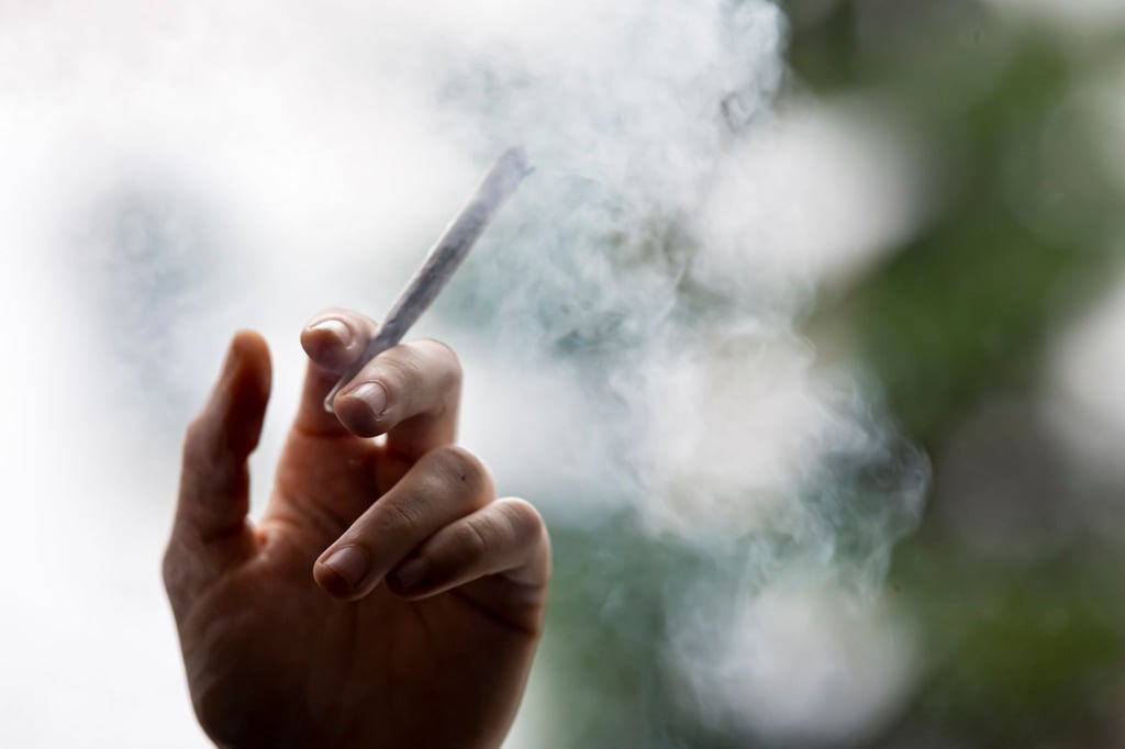 Ein Mann hält einen Joint in der Hand.