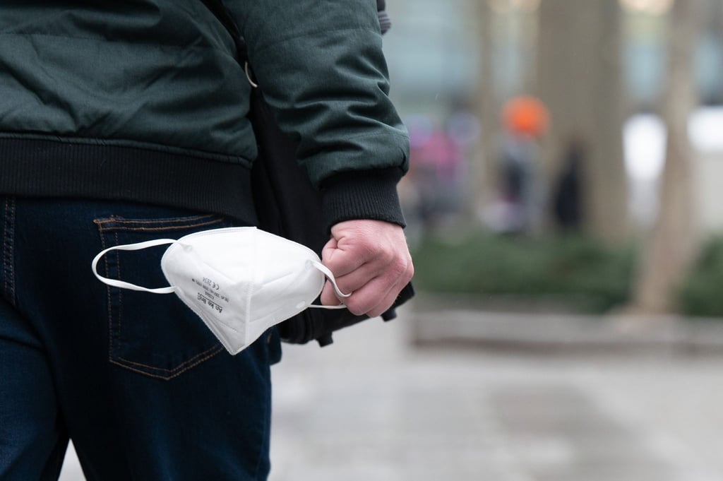 Ein Mann hält eine FFP2-Maske in der Hand.