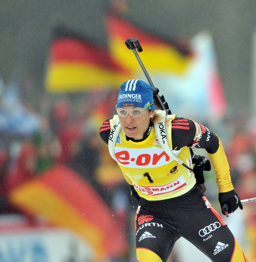 Die deutsche Biathletin Magdalena Neuner läuft an einem Fahnenmeer vorbei.