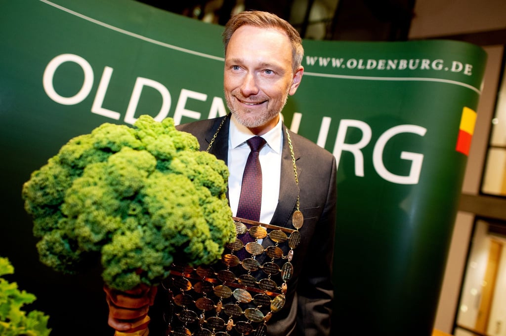 Der neue Oldenburger Grünkohlkönig Christian Lindner (FDP), Bundesfinanzminister, trägt eine Kohlkette und hält eine Grünkohlpflanze, auch bekannt als „Oldenburger Palme“, in den Händen.