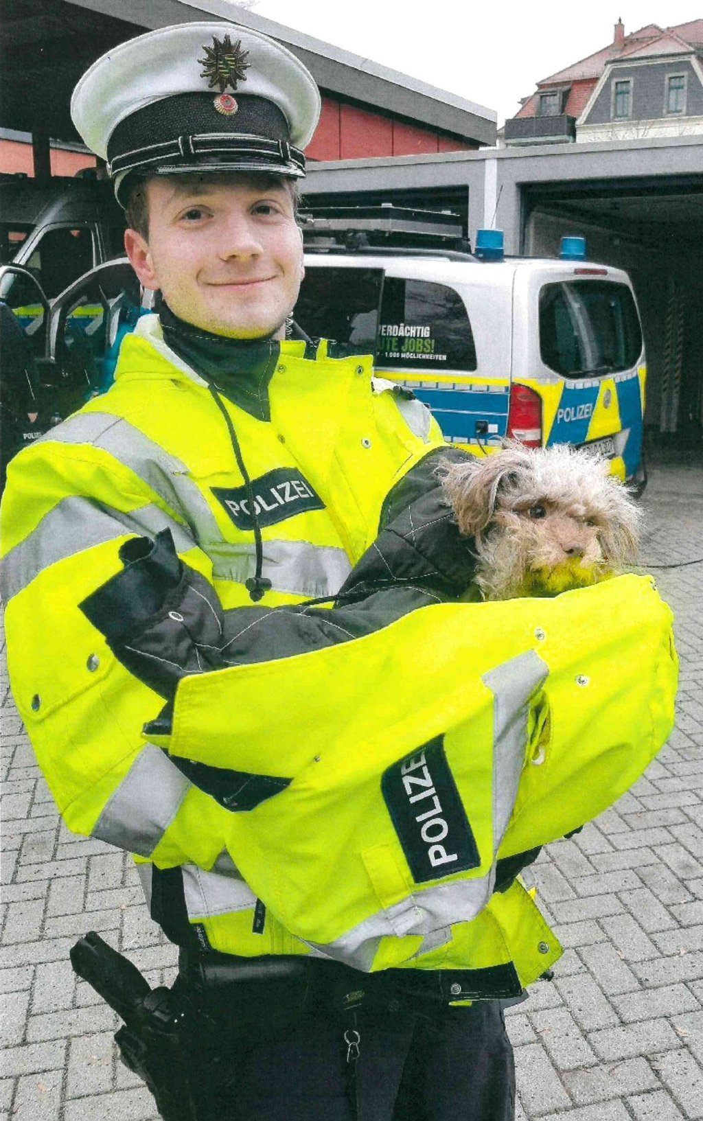 Ein Beamter der Autobahnpolizei hält einen Hund der Rasse Bolonka Zwetna in den Armen.
