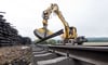 Arbeiter zerlegen mit einem Bagger alte Bahnschienen während der Sanierung einer ICE-Trasse in Niedersachsen.