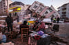 Leben in der Zerstörung: Menschen sitzen vor eingestürzten Gebäuden in Golbasi, Türkei.