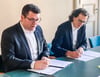 Landrat Christian Tylsch (l.) und René Pessier, Geschäftsführer des Dresdner Unternehmens, unterzeichnen den Vertrag.