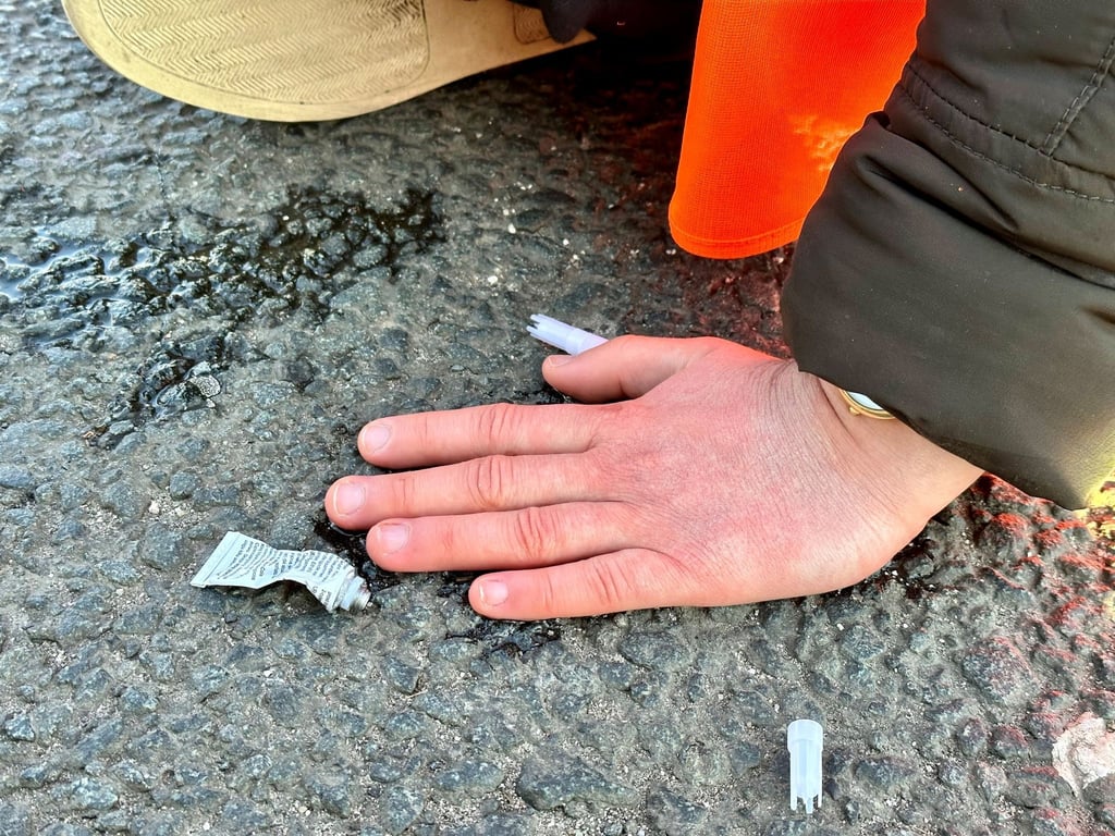 Eine Klimaaktivistin hat sich mit der Hand auf einer Hauptverkehrsstraße festgeklebt.