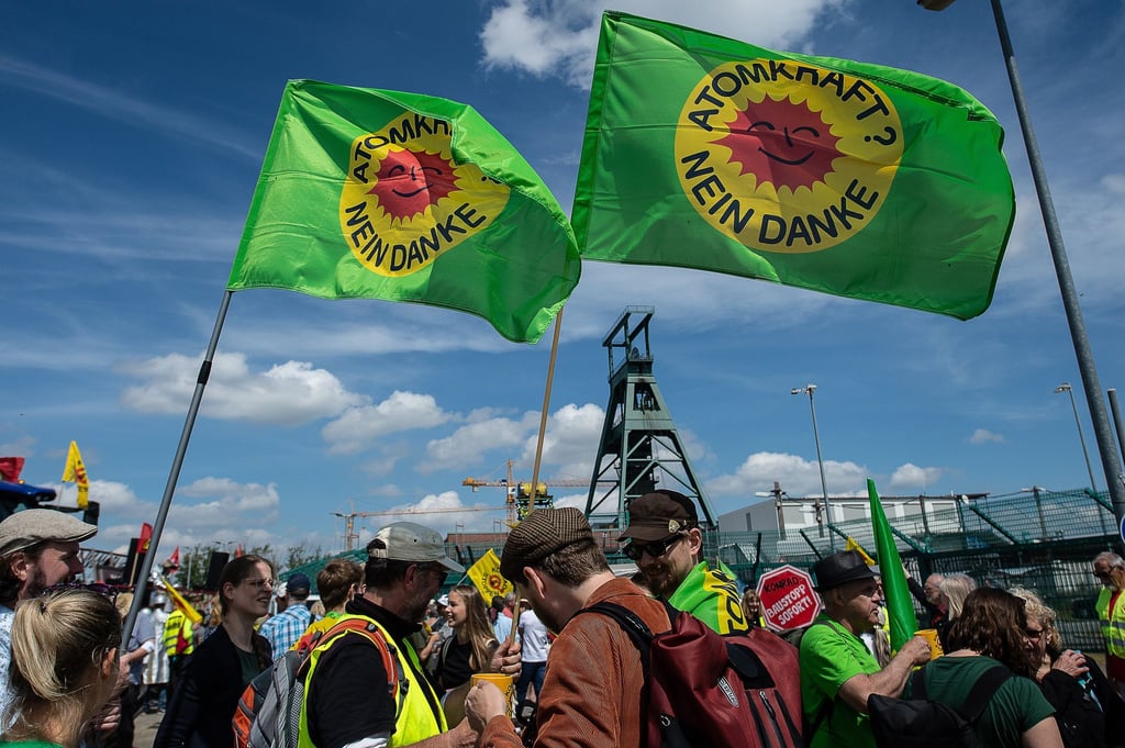 Demonstranten stehen mit Flaggen vor dem ehemaligen Erzbergwerk „Schacht Konrad“.