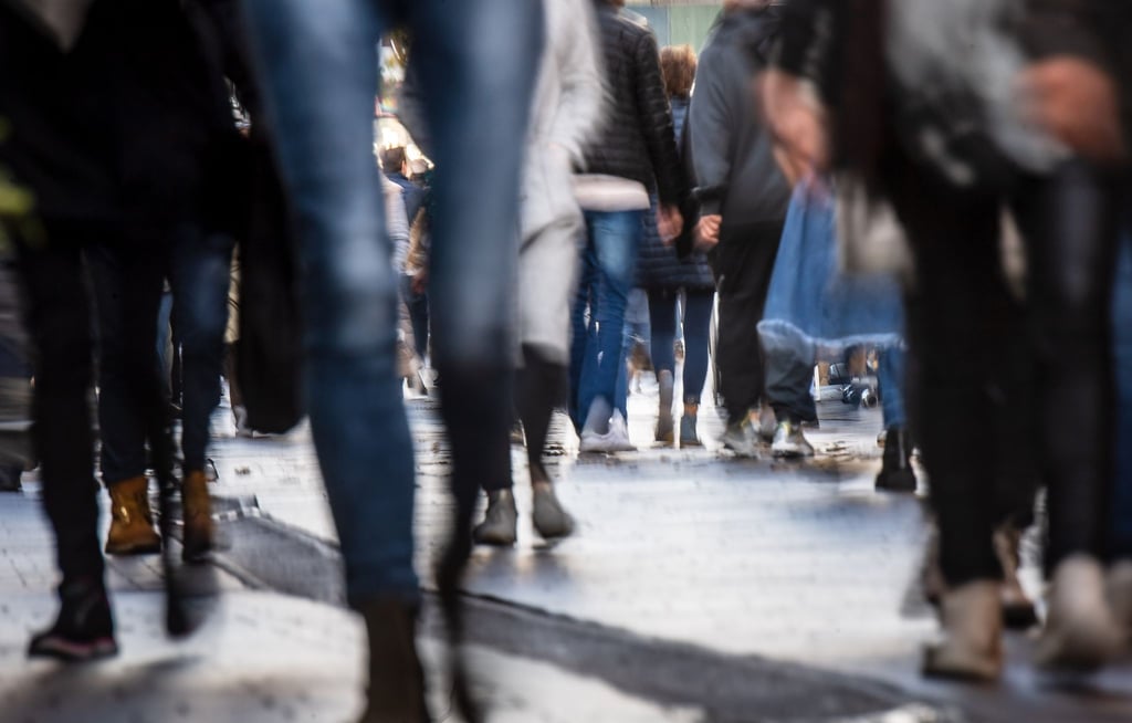 Passanten gehen durch eine Fußgängerzone.