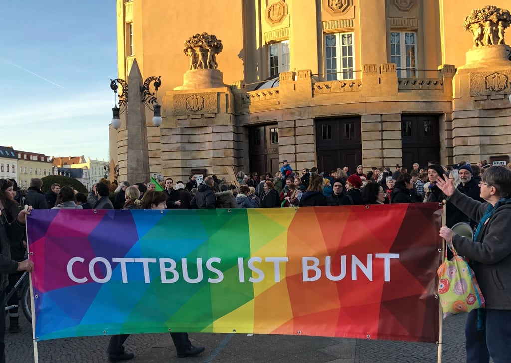 Demonstrierende halten ein Transparent mit der Aufschrift "„Cottbus ist bunt“" in die Höhe.