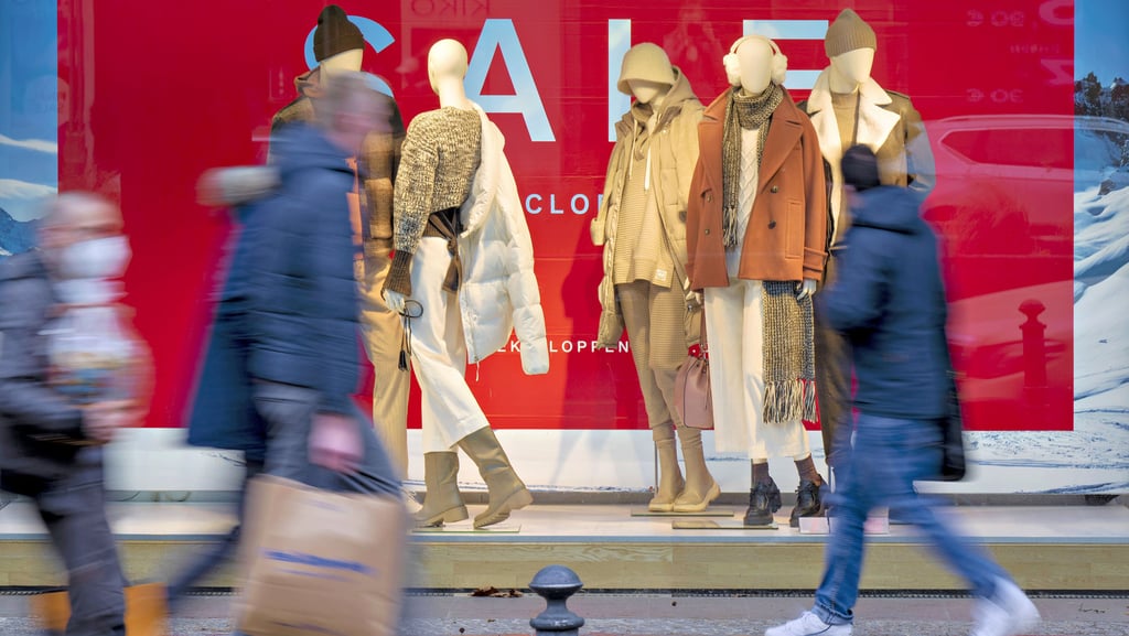 Passanten passieren die Schaufenster eines Textilhändlers.