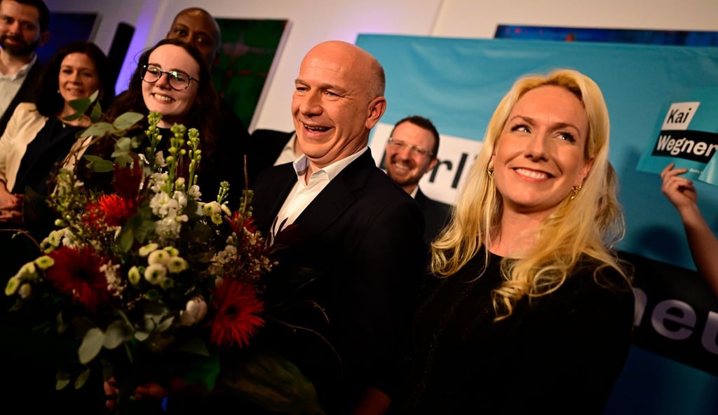 CDU-Spitzenkandidat Kai Wegner steht mit einem Blumenstrauß auf der Bühne der CDU-Wahlparty.