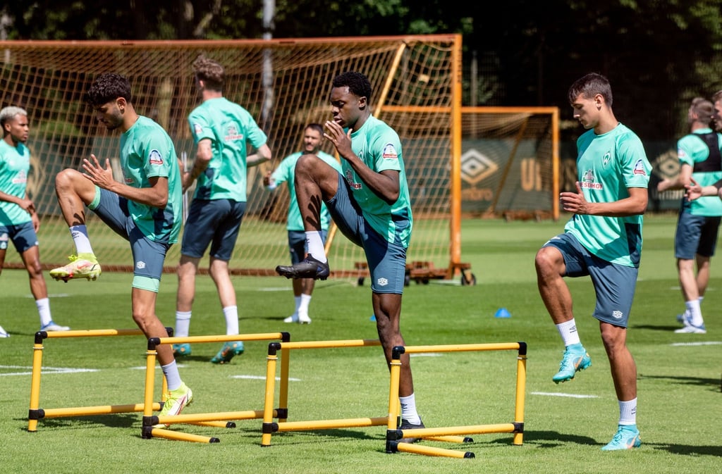 Die Mannschaft von Werder Bremen wärmt sich auf dem Trainingsgelände auf.