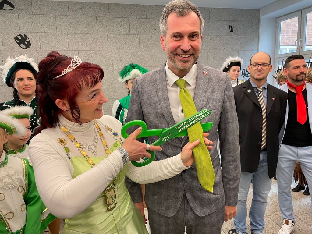 Ein Karnevalistin schneidet die Krawatte von Oberbürgermeister Tobias Schick ab.