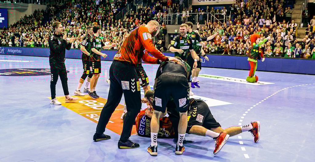 Ausgelassene Stimmung beim SC Magdeburg: Während Mike Jensen, Kay Smits und Lucas Meister (v. l.) auf Torwart Nikola Portner stürzen, feiern Philipp Weber und Co. im Hintergrund mit den Fans den Sieg gegen Veszprém.