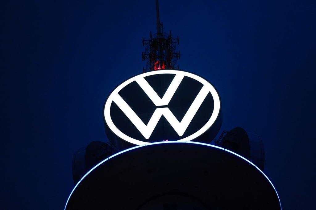 Das Volkswagen Logo leuchtet auf dem VW-Tower vor dunklem Himmel.