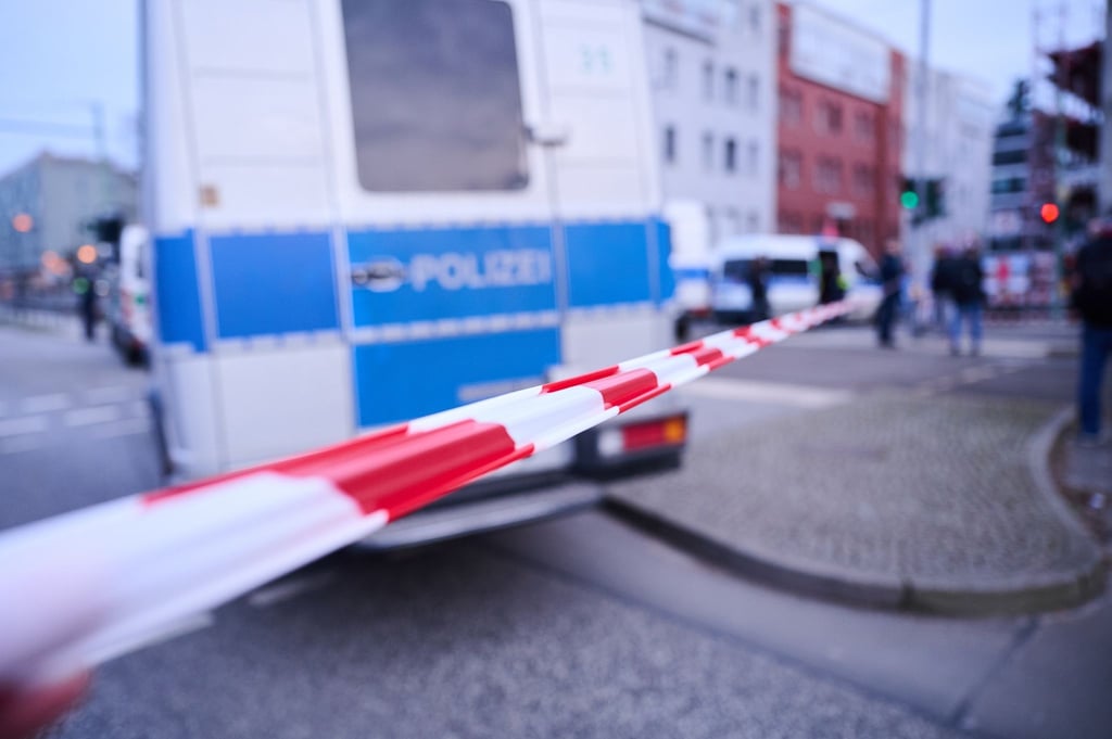 Nach einem ausgelösten Amokalarm in einem Berliner Jobcenter stehen Einsatzfahrzeuge hinter der Absperrung an der Landsberger Allee.