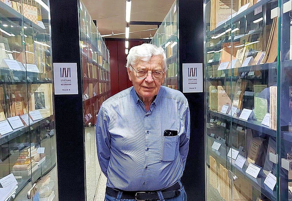 Professor Wolfram Neumann zwischen Regalen, in denen die Bücher der Neumann-Stiftung aufbewahrt werden. 
