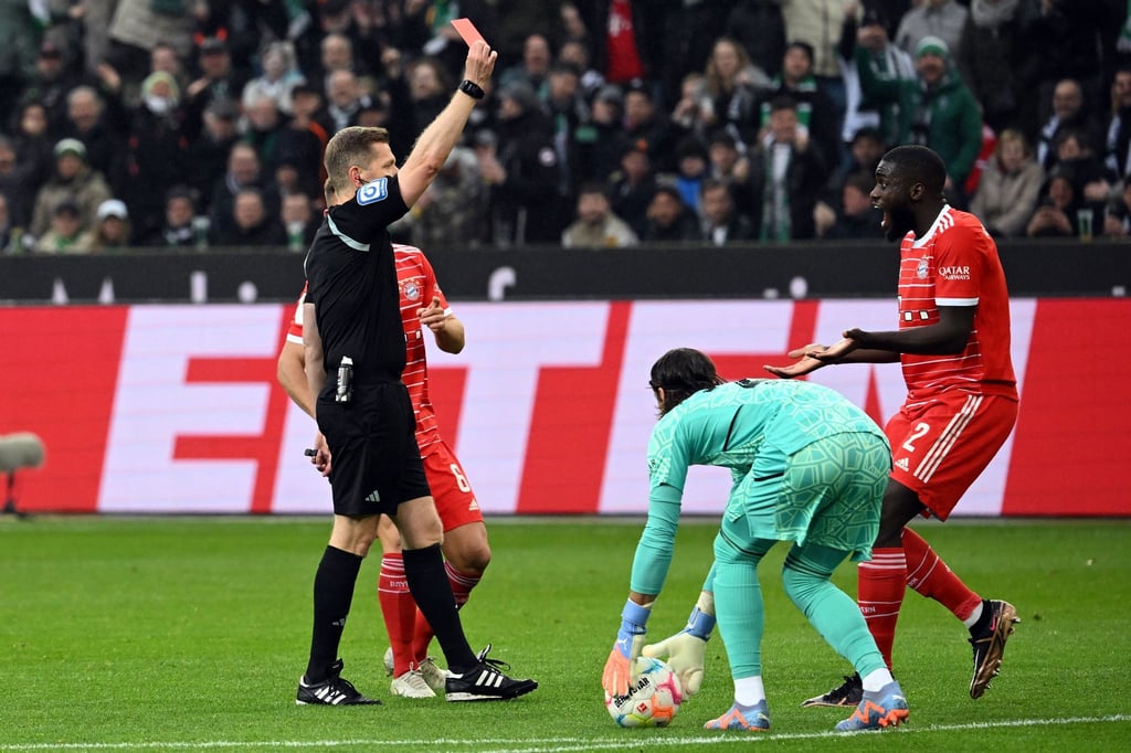 Schiedsrichter Tobias Welz zeigt Bayerns Dayot Upamecano (r) die rote Karte.