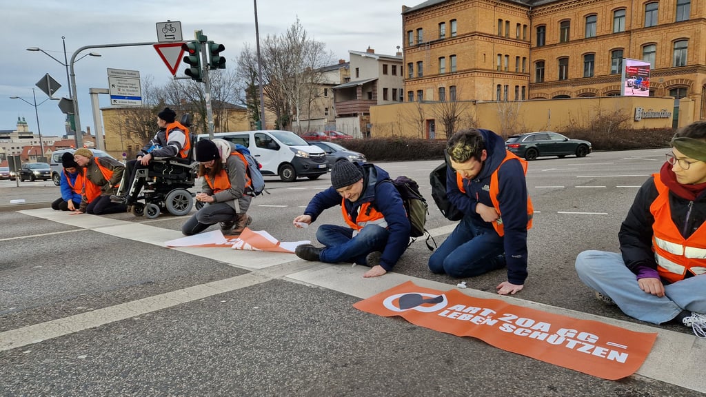 Klimaaktivisten von "Letzte Generation" blockieren am Montagmorgen eine Straße am Rand der Innenstadt von Halle.