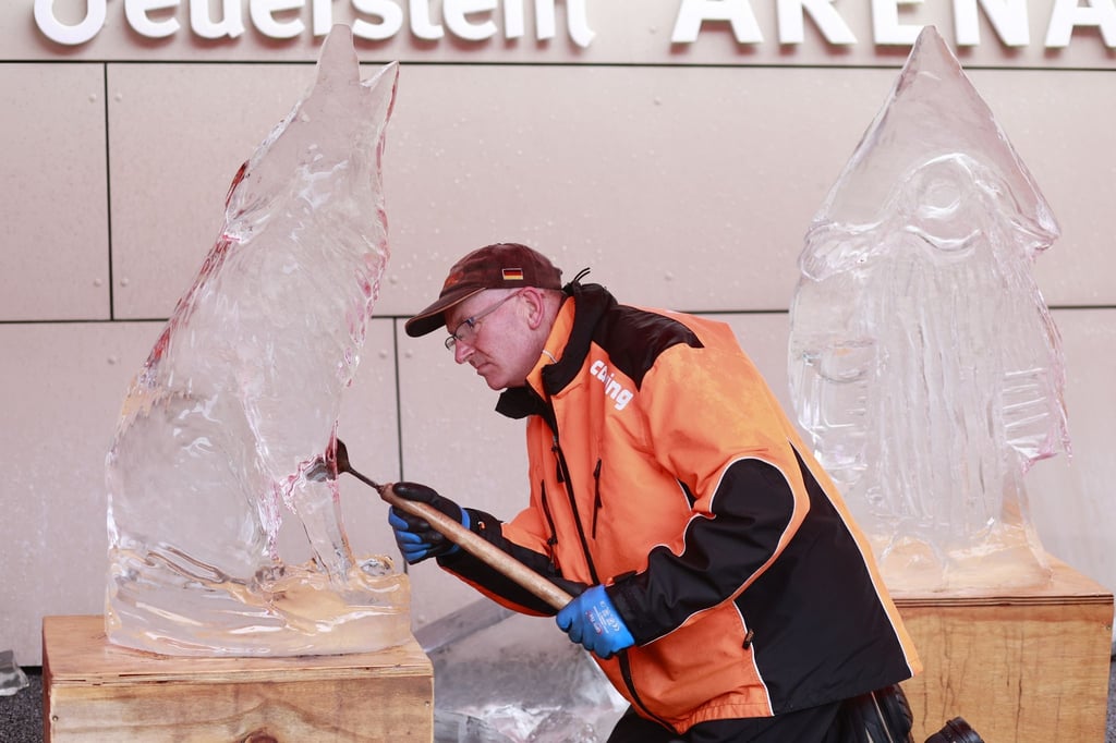 Bernd Winter bearbeitet einen Eisblock mit einem Meißel.