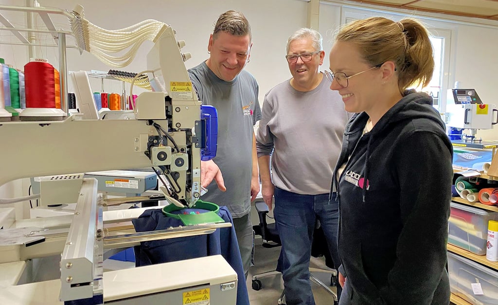 Chef Olaf Ladde (Mitte) mit Mitarbeiterin und Tochter Anne-Kathrin Büttner und Maurice Wurzendorf an der Stickereimaschine.
