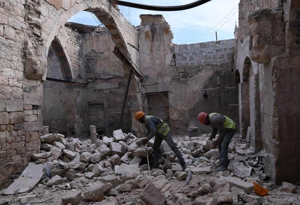 Bauarbeiter beim Wiederaufbau des Khabiya Markts im historischen Viertel Souk der Altstadt von Aleppo zwischen Trümmern eines zerstörten Gebäudes.