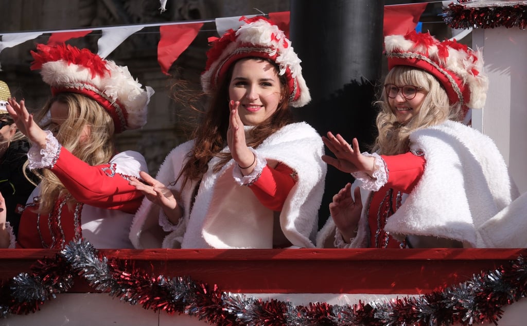 Akteurinnen von Karnevalsvereinen auf einem Festwagen.