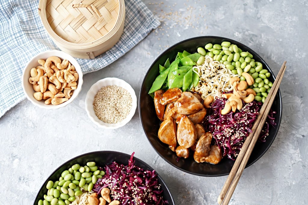 Auf den Mienudeln sind die bunten Zutaten der asiatischen Bowl mit Sesam und Sojasoße gewürzt und nach dem Baukastenprinzip angeordnet.