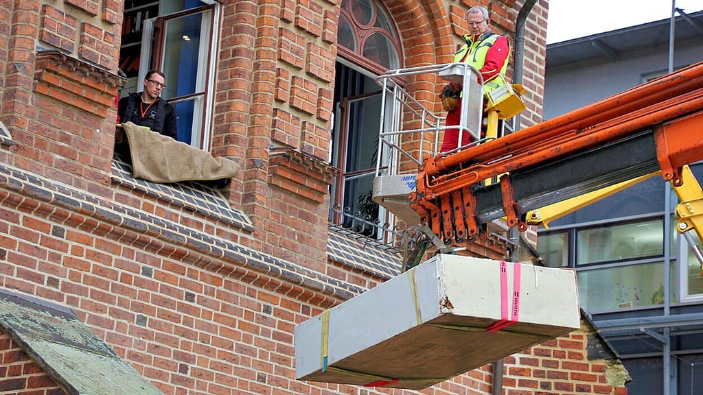 Tresor im Schwebeflug: Mit Spanngurten und an einem Haken befestigt, findet das Schwergewicht vom Rathaus Stendal seinen Weg ins Freie.