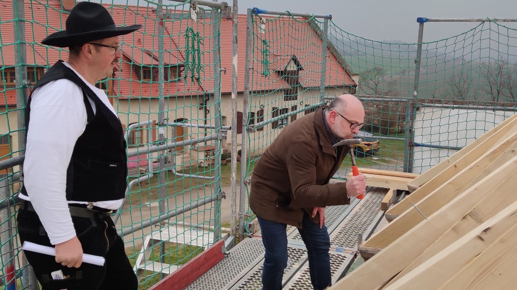 Jörg Giessmann, Baureferent der Kulturstiftung Sachsen-Anhalt, schlägt den symbolischen letzten Nagel ins Holz. Zimmerer Jörg Lamster sieht ihm dabei zu.
