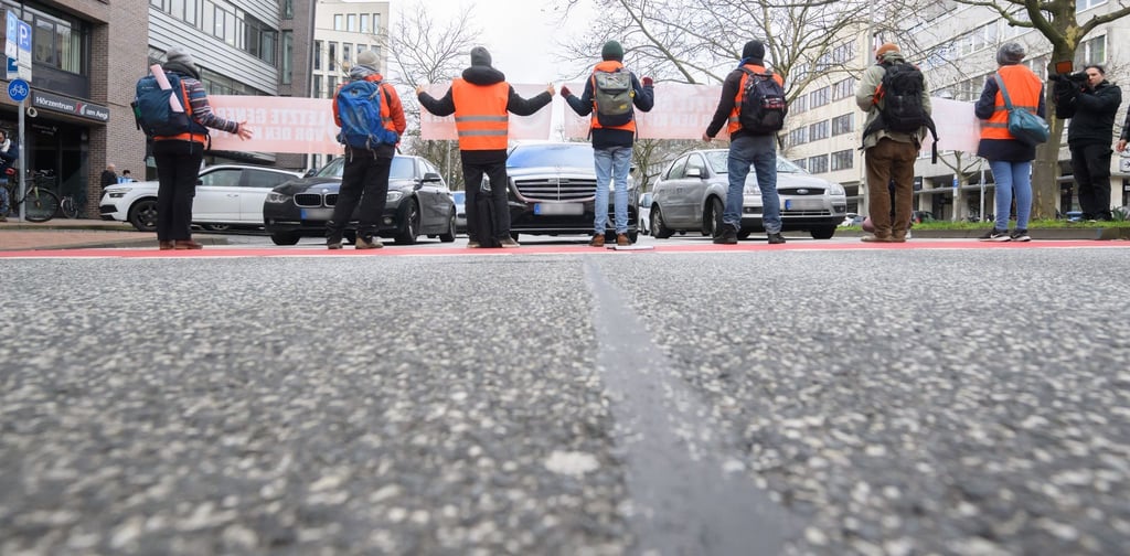 Aktivisten der Gruppierung „Letzte Generation“ blockieren auf der Hildesheimer Straße am Aegidientorplatz den Verkehr.