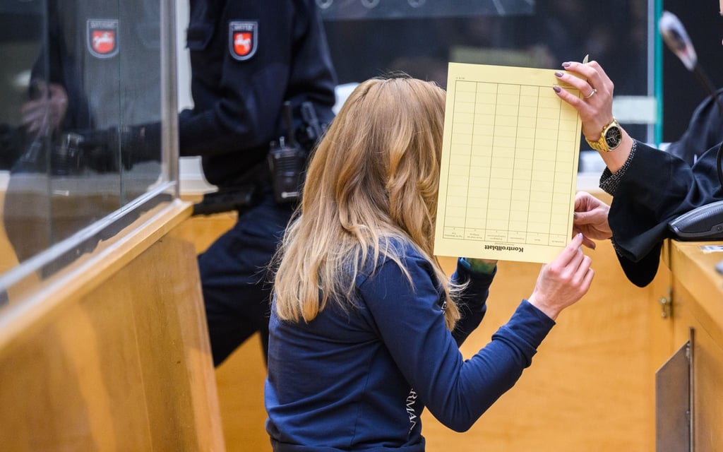 Die Angeklagte sitzt mit verdecktem Gesicht im Gerichtssaal im Landgericht.