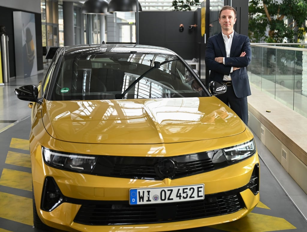 Florian Huettl, Geschäftsführer der Opel Automobile GmbH, posiert in der Unternehmenszentrale neben einem Opel Astra.