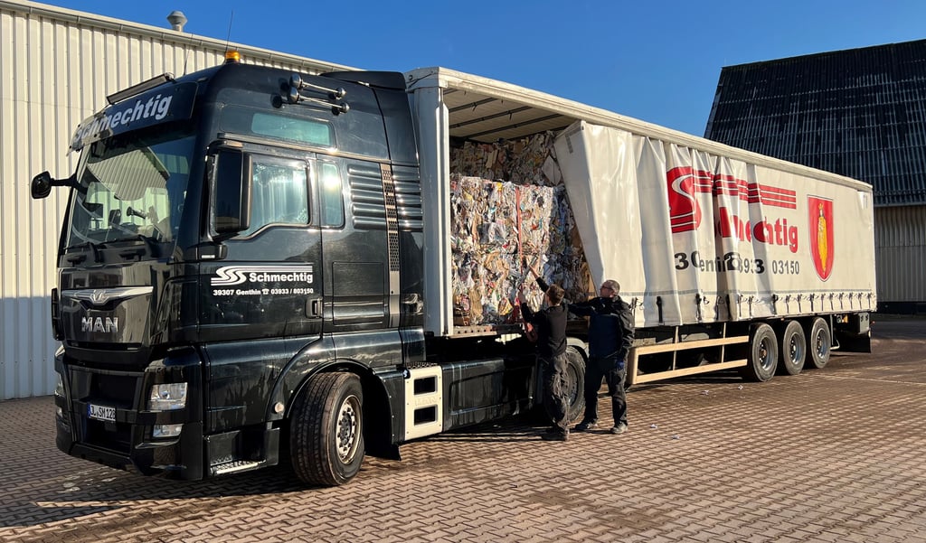 Mitarbeiter der Spedition Schmechtig bei der Arbeit. Ein Auszubildender wird von einem Kraftfahrer im Sichern beim Verladen von Altpapierballen unterwiesen.