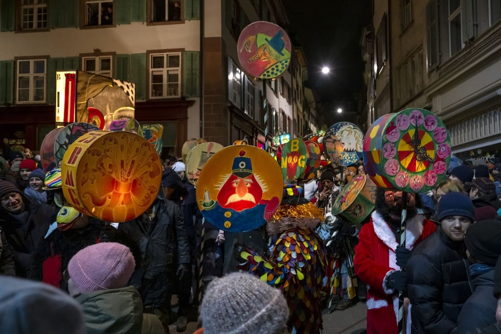 Fasnachtscliquen mit Laternen ziehen durch die Straßen am Morgestraich in Basel.