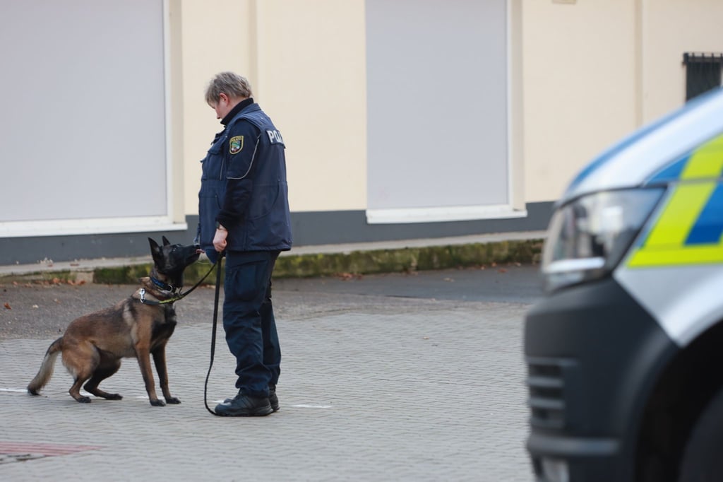 Ein Polizist und ein Spürhund stehen vor einem Impfzentrum in Quedlinburg.