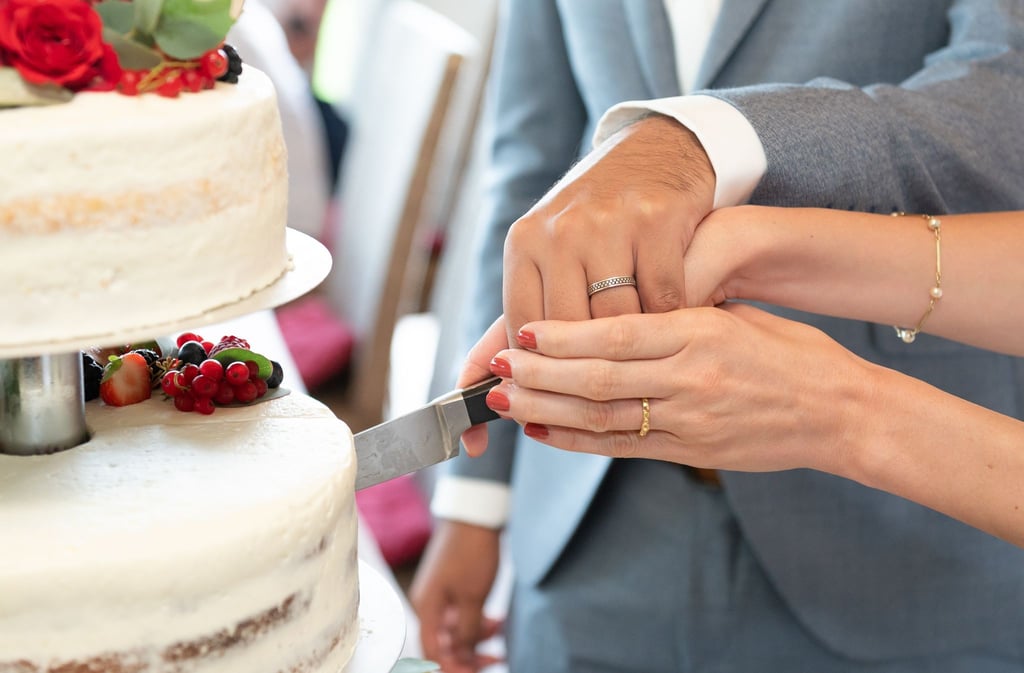 Ein Brautpaar schneidet während der Hochzeitsfeier die Hochzeitstorte an.