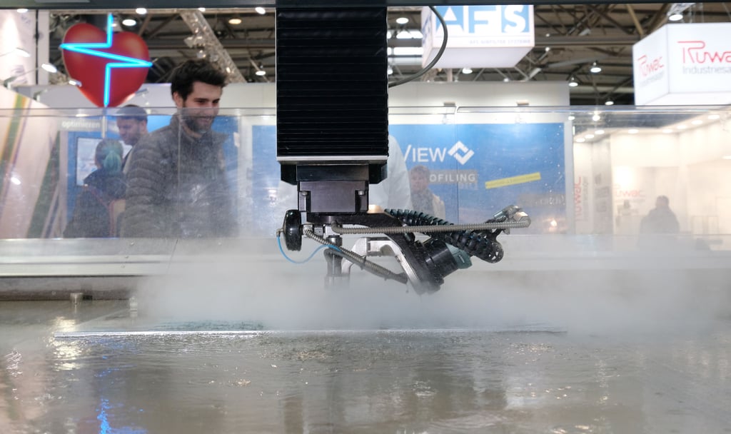 Eine Wasserstrahlanlage der Firma "Flow" schneidet an einem Stand der Messe Intec eine Metallplatte.