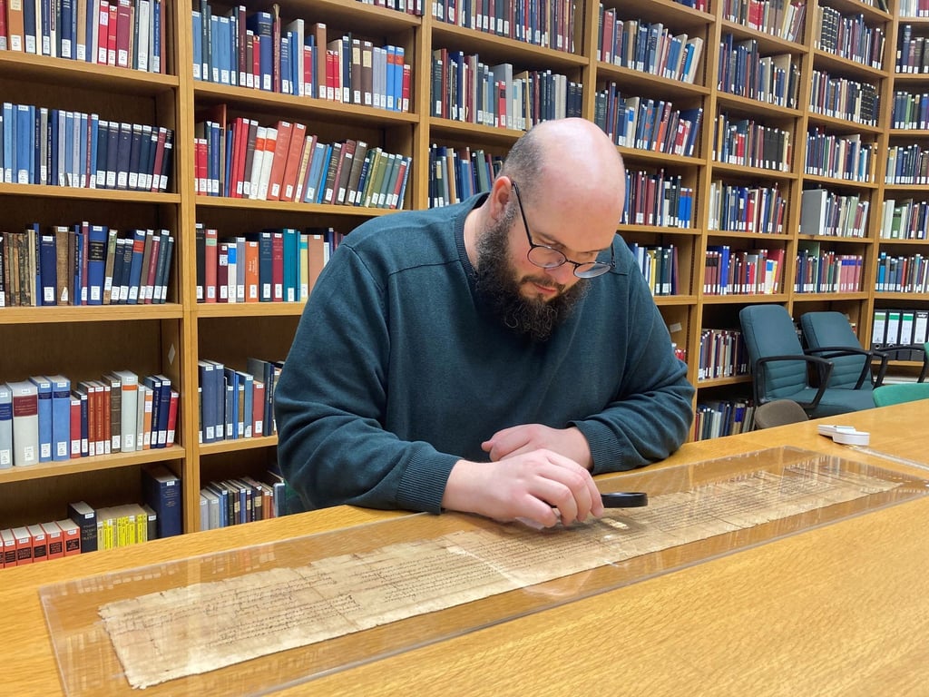 Der Papyrologie-Junior-Professor Patrick Reinard studiert den Text einer Papyrus-Rolle an der Universität Trier.