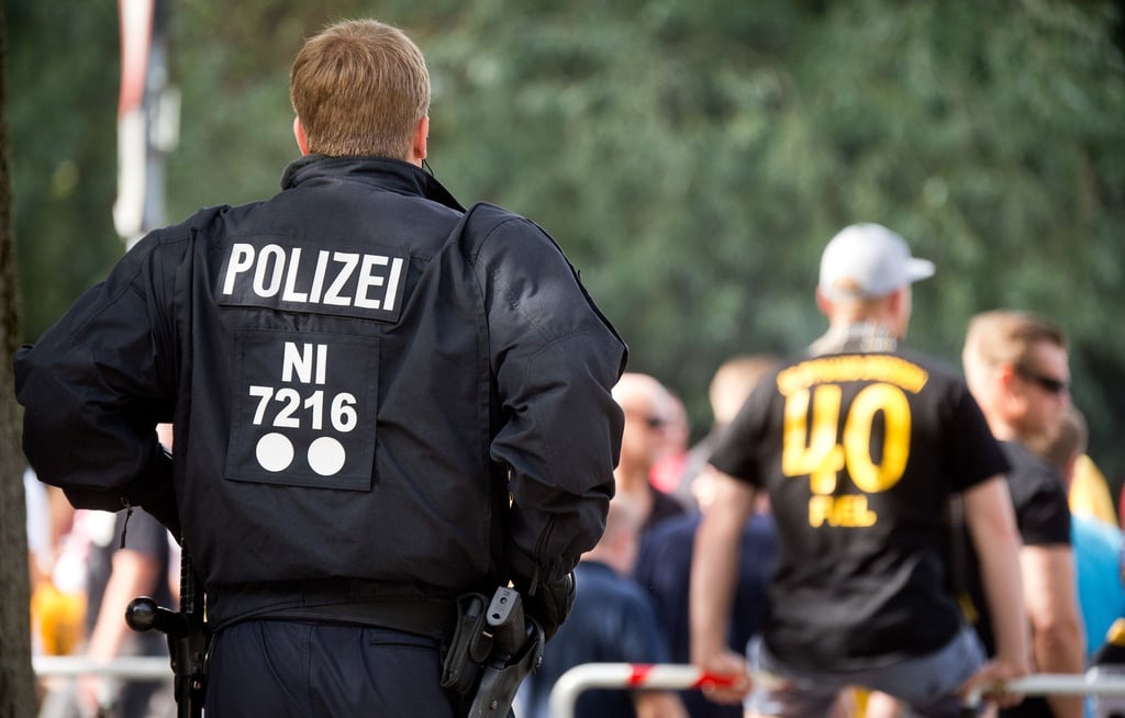 Ein Polizist steht vor einem Fußballspiel vor einer Arena.