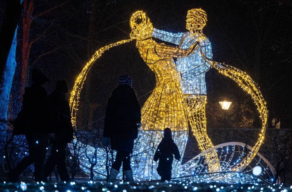 Besucher flanieren durch den illuminierten Schlosspark Lichtenwalde.