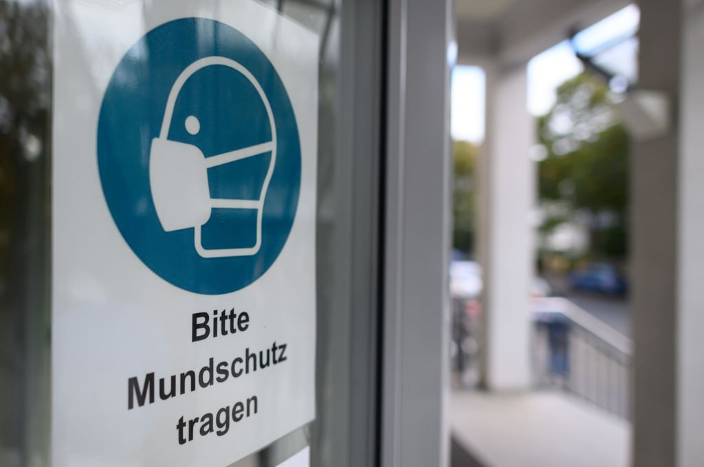 Ein Schild „Bitte Mundschutz tragen“ ist am Eingang eines Krankenhauses angebracht.