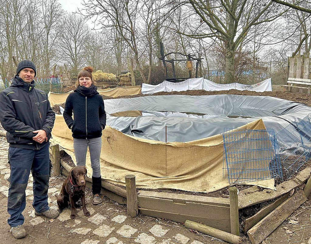 Mario Körner-Hinz und Antje Petschulat mit Hündin Rosie vor dem fast fertigen Teich auf dem Magdeburger Bauspielplatz.