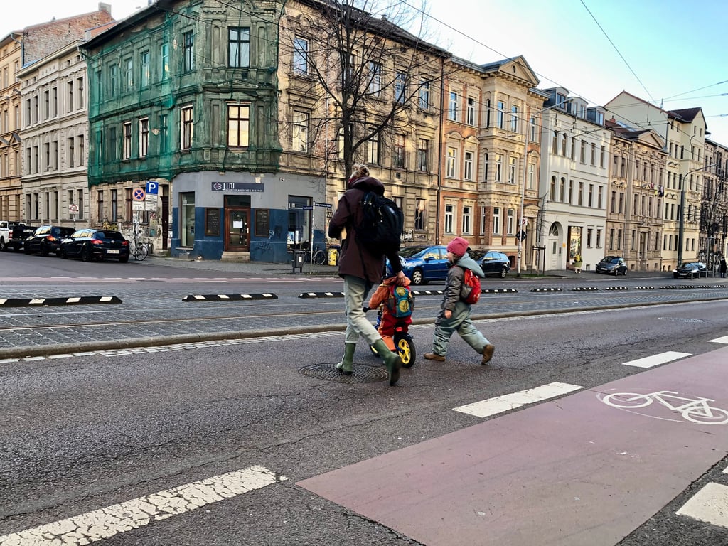 Eine Mutter überquert die Ludwig-Wucherer-Straße mit ihren beiden Kindern. Sie geht nicht den Umweg über die Ampel an der nächsten Kreuzung.